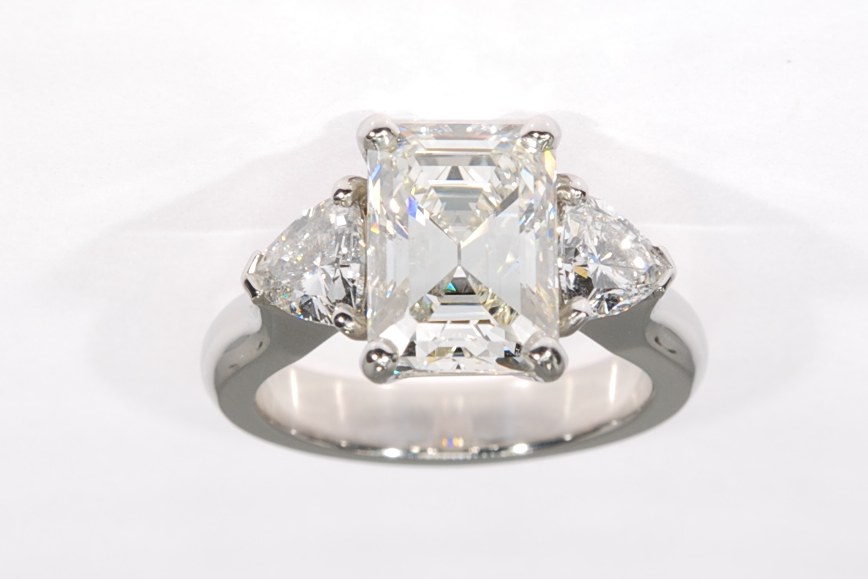 Platinum ring with a large emerald-cut diamond and a diamond on each side