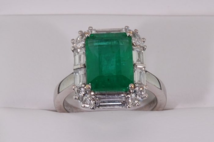 Emerald-cut green gemstone ring surrounded by baguette and round diamonds