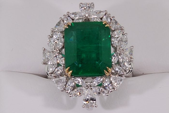 Emerald-cut green gemstone ring with a cluster of marquise and pear-shaped diamonds