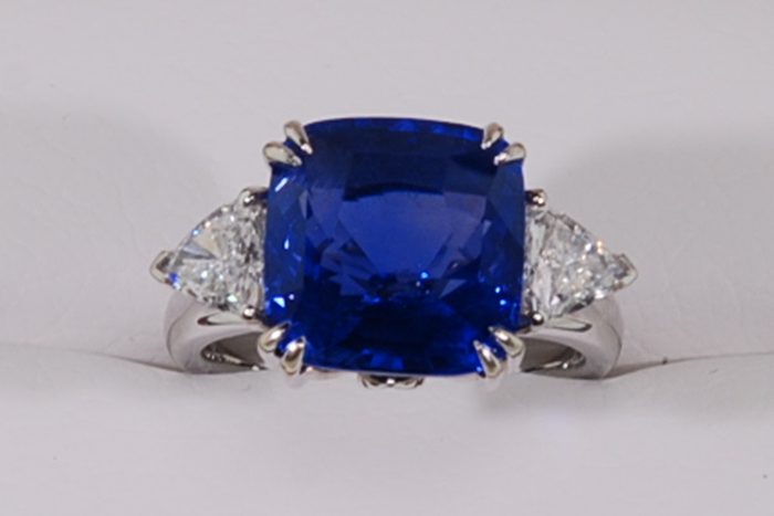 Cushion-cut blue gemstone ring with a pear-shaped diamond on each side