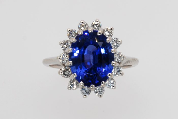 Oval blue gemstone ring with a diamond halo