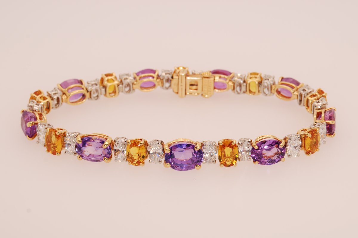 Gold bracelet with oval purple, orange, and pink gemstones alternating with oval diamonds