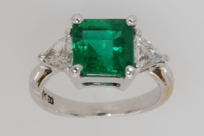 Green gemstone ring with two side diamonds