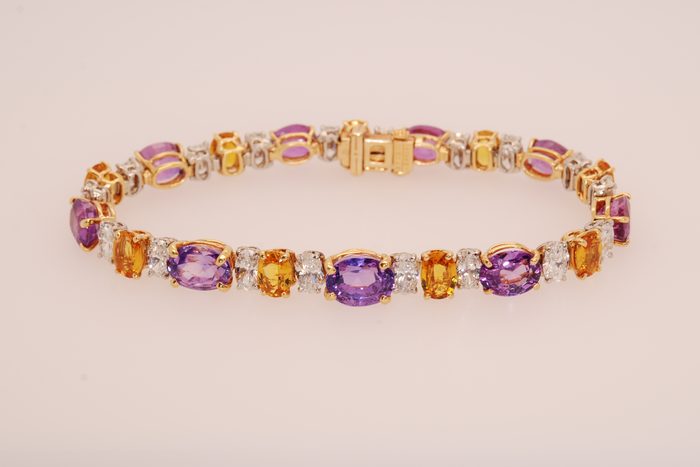 Gold bracelet with oval purple, orange, and pink gemstones alternating with diamonds